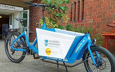 Fahrrad mit Lastkorb vor einem Gebäude, vermutlich für Transportaufgaben.