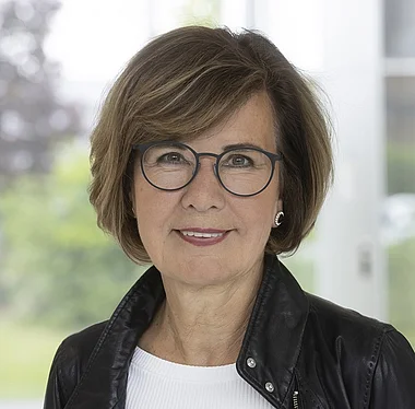 Frau in Lederjacke lächelt freundlich in die Kamera.