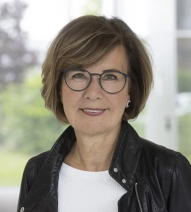 Frau in Lederjacke lächelt freundlich in die Kamera.