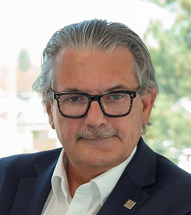 Ein Mann im Anzug lächelt freundlich in die Kamera.