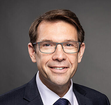 Professioneller Mann im Anzug, lächelnd, für ein Firmenporträt.