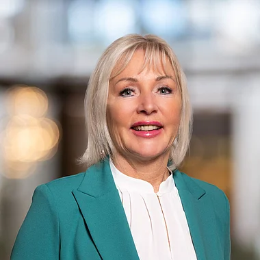 Frau in Blazer und Schmuck, professionelles Porträt.