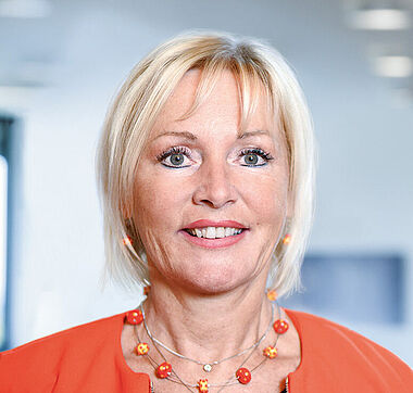 Frau in Blazer und Schmuck, professionelles Porträt.